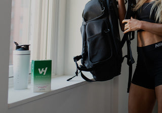 Vitahustle Reds and Greens superfood powder on a window sill and fit woman loading her backpack